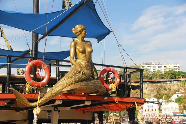 sculpture of a mermaid on the deck of ship on the seashore