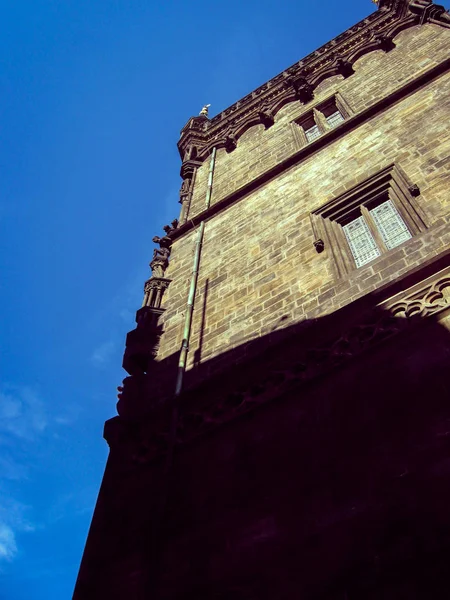 Hermosa torre de una antigua casa de piedra sobre un fondo de azul al — Foto de Stock