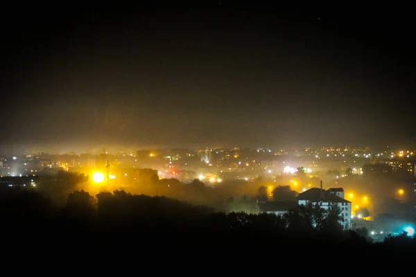 Uitzicht op de nacht stad bedekt met mist in de straatverlichting en — Stockfoto