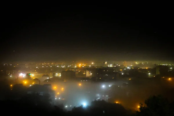 View of the night city covered with fog in the street lights and