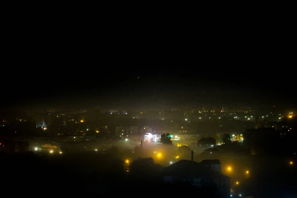Vista da cidade noturna coberta com nevoeiro nas luzes da rua e — Fotografia de Stock