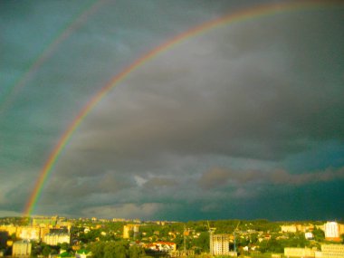 Fırtına sonrası şehir manzarası. Şehrin üzerinde çifte gökkuşağı