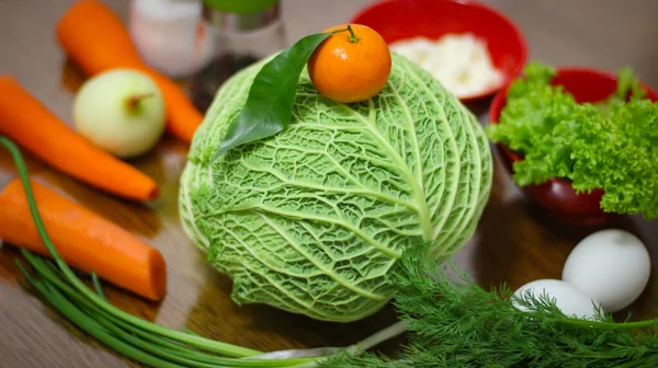 Ingredients for a delicious salad. Cabbage, carrots, salad leaves, parsley greens, onions, mandarin, salt, black pepper, boiled chicken eggs.