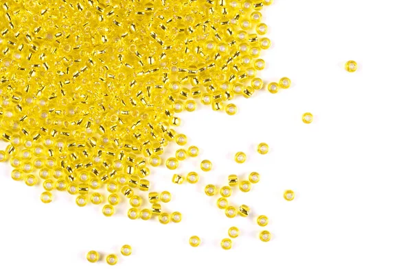 Yellow beads scattered beads on a white background, top view, costume jewelry