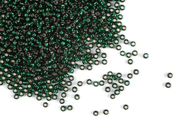 Green beads scattered beads on a white background, top view, costume jewelry