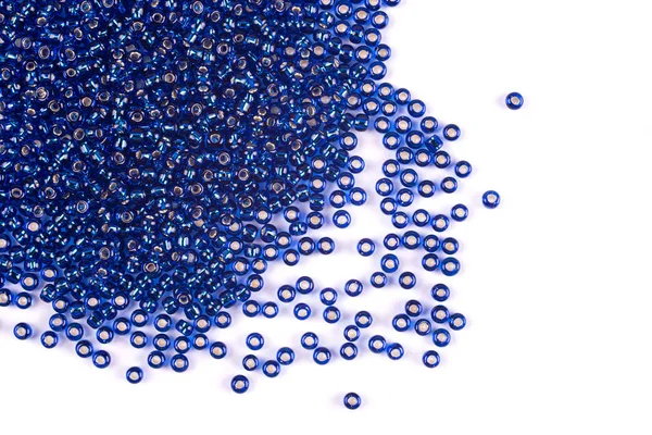 Blue beads scattered beads on a white background, top view, costume jewelry