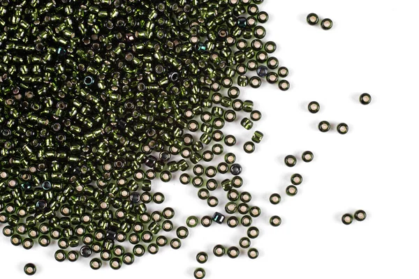 Green beads scattered beads on a white background, top view, costume jewelry