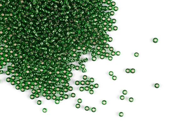 Green beads scattered beads on a white background, top view, costume jewelry