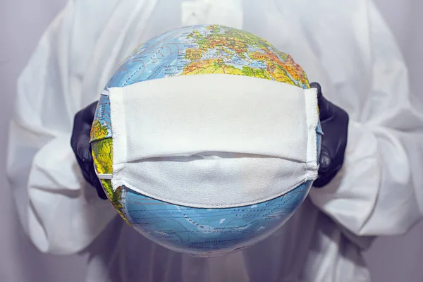 Global Coronavirus Pandemic. A World Globe With A Medical Mask. The man in the medical mask