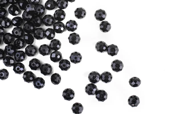 Black beads are scattered on a white background