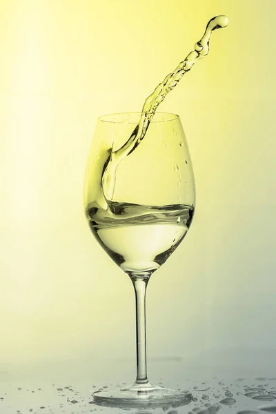 Water spatten uit een hoog glas wijn. — Stockfoto