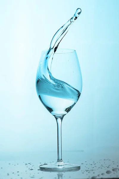 Víz fröccsen ki egy magas pohár. — Stock Fotó