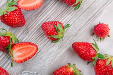 Beyaz ahşap zemin üzerinde bir kapta sulu taze çilek