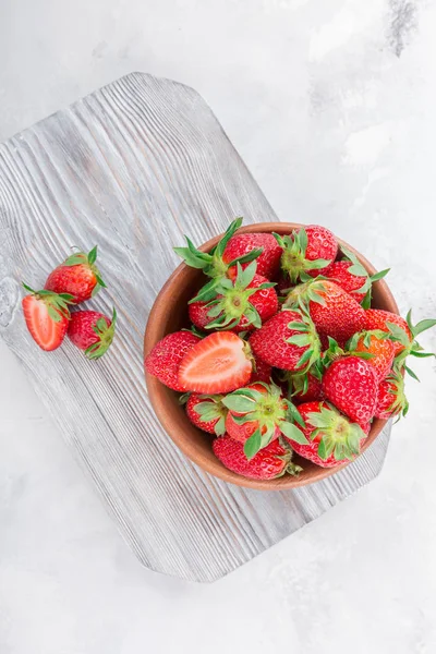 Beyaz ahşap zemin üzerinde bir kapta sulu taze çilek