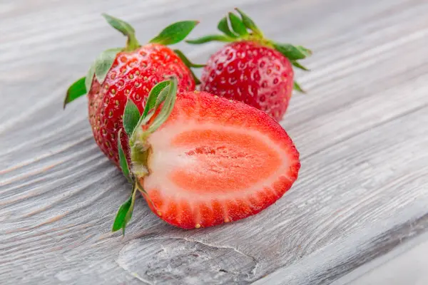 Beyaz ahşap zemin üzerinde bir kapta sulu taze çilek