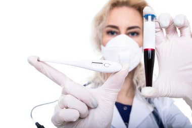 Doktor kızın elinde içinde kan ve elektronik termometre olan bir test tüpü tutuyor. Hastalık önleme