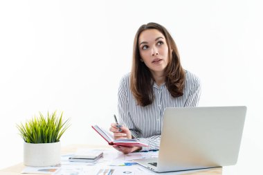 Ofis kıyafet yönetmeliğinde bir kız masasında oturmuş iş yapıyor.