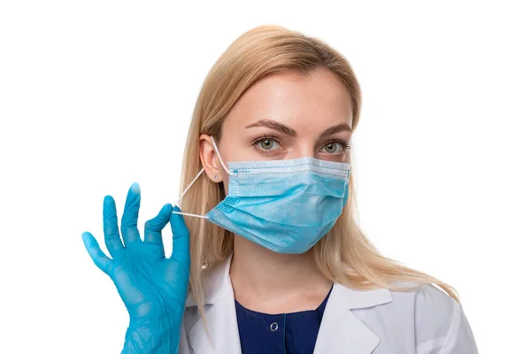 Beyaz arka planda koruyucu maskeli ve eldivenli bir doktorun portresi. Virüsün yayılmasını önleme kavramı