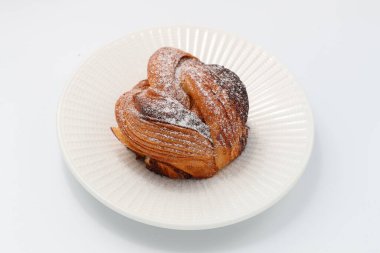 Beyaz bir tabakta taze pişmiş tarçınlı çörek.