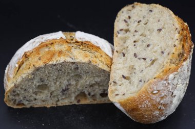 Koyu arkaplanda baharatlarla yarım ekmek kes.