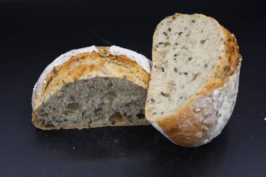 Koyu arkaplanda baharatlarla yarım ekmek kes.