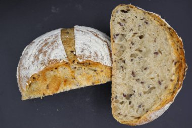 Koyu arkaplanda baharatlarla yarım ekmek kes.