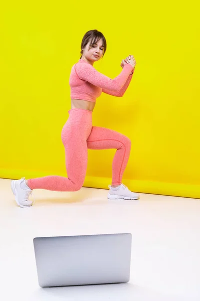 Sportowa Dziewczyna Trenuje Domu Online Oglądając Filmy Laptopie Żółtym Tle — Zdjęcie stockowe