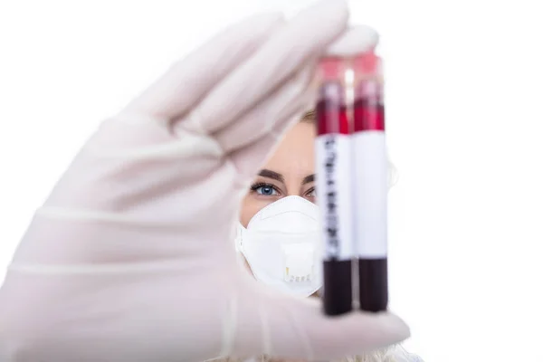 Close-up face of a female doctor who holds test tubes with blood in her hands