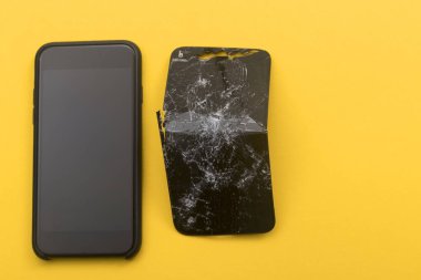 Telefon, sarı arka planda kırık bir telefonun yanında duruyor. Telefon tamir kavramı