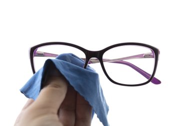 Gözlükleri silen mavi bir bez ile yakın plan bir el. İzole edilmiş