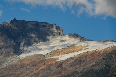 Bulutların karla kaplı olduğu yüksek bir dağ
