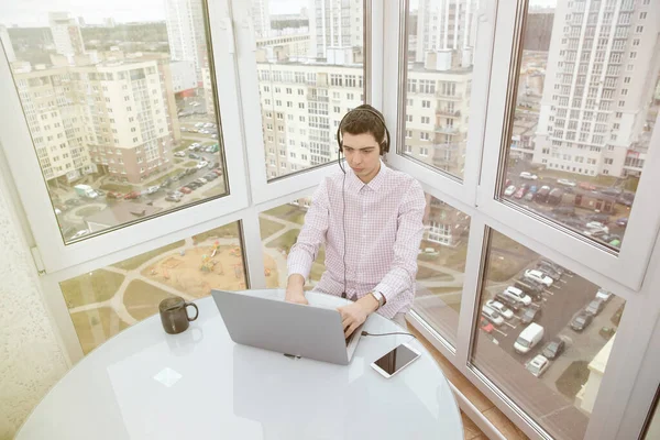 The guy works remotely from home at a computer