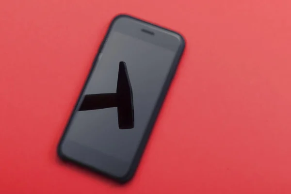 锤子在手机屏幕上的红色背景上反射出来 电话维修概念 — 图库照片