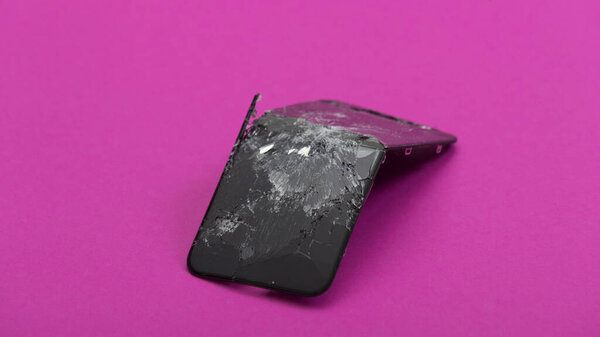 Broken and bent the screen of the phone on a pink background.