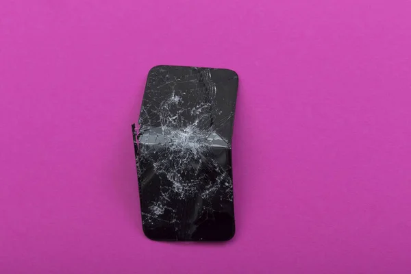 Broken and bent the screen of the phone on a pink background.