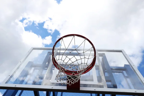 Basketbol potası, bulutlardaki mavi gökyüzünün arka planında bir sokak basketbol sahasında.