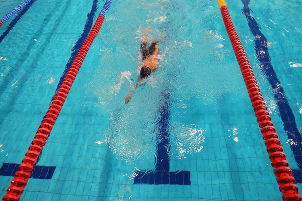 Athlete trains in the pool with clean water. Top view