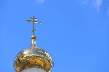 Kilisenin çatısındaki Ortodoks altın haçı mavi gökyüzünün arka planına yakın çekim