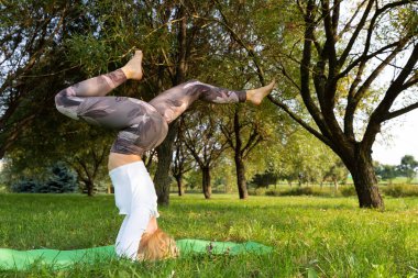 Kız parkta yoga yaparken kafasının üstünde duruyor.