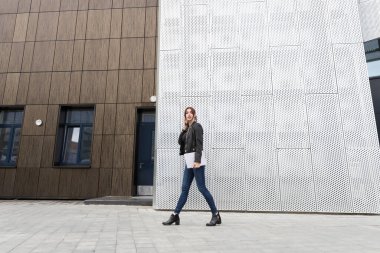 Kızıl saçlı kız telefonda konuşuyor ve elinde dizüstü bilgisayar var. Ofiste dolaşıyorum.