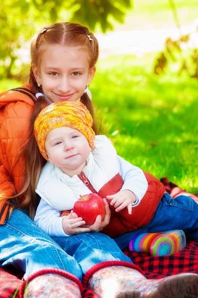Девушка с маленьким мальчиком в парке осенью с яблоками — стоковое фото