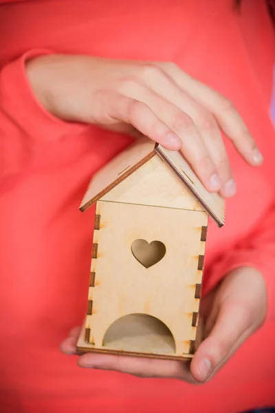 Women's handen met een houten huis — Stockfoto