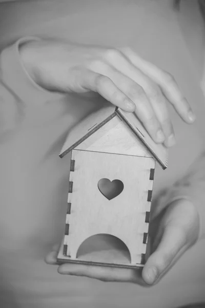 Women's handen met een houten huis — Stockfoto