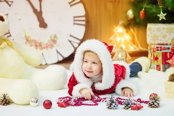 Ragazzino su un albero di Natale con dei regali in mano. Natale. Regali. L'umore festivo. Infanzia. — Foto Stock