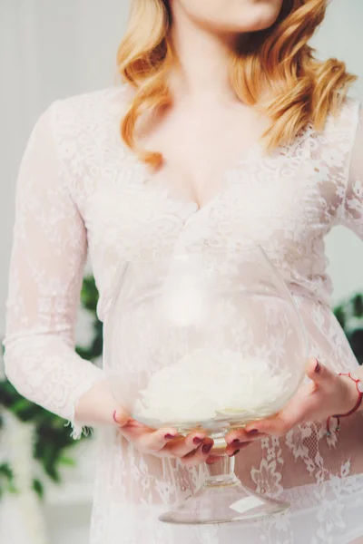 Belle fille avec des fleurs blanches à la main dans une robe de chambre blanche. Jeune mariée en blanc le matin — Photo