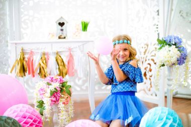 Bir portre bir güzel küçük kız gülüyor bir stüdyoda birçok renk balon dekore edilmiş