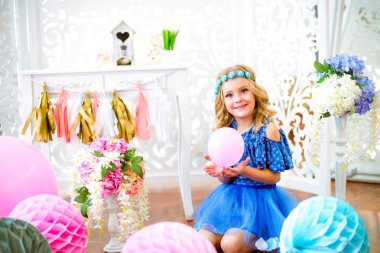 Bir portre bir güzel küçük kız gülüyor bir stüdyoda birçok renk balon dekore edilmiş