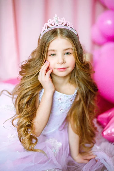 女孩与金发长发粉红色的礼服公主和皇冠上的气球周围 — 图库照片