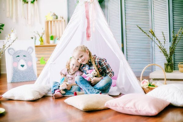  Маленькие симпатичные сестры девочки готовятся к празднованию Пасхи. Дети веселятся с пасхальным украшением сидя на полу дома
.