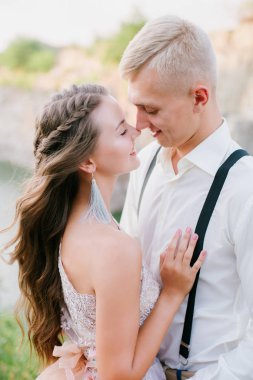 Zarif kıvırcık gelin ve damat göl arka plan üzerine açık havada. Damat ve gelin. gelinlik. Gelin düğün buket çiçek